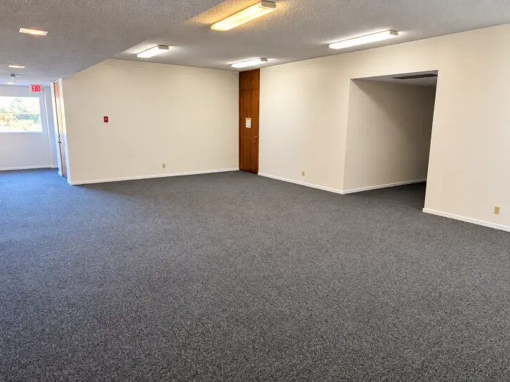 Empty carpeted multipurpose room with bright windows