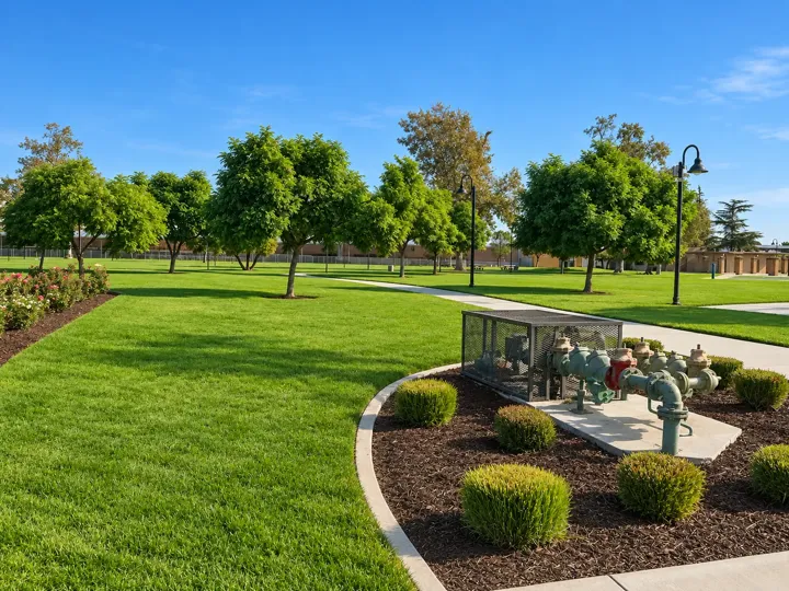 Green public park with trees, lawn and walking paths across the street from the church