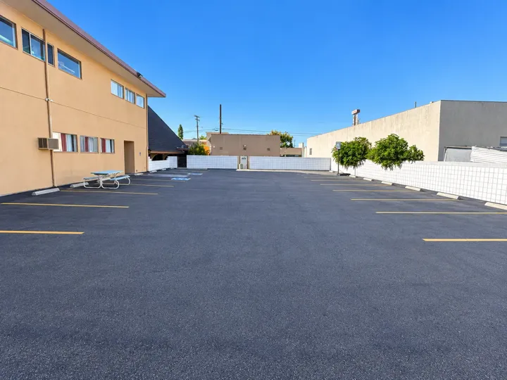 Rear parking lot beside a two-story campus building with a picnic table and accessible spaces