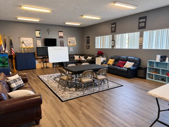 Lounge meeting room with leather sofas, a rug, a folding table with chairs and a flip chart
