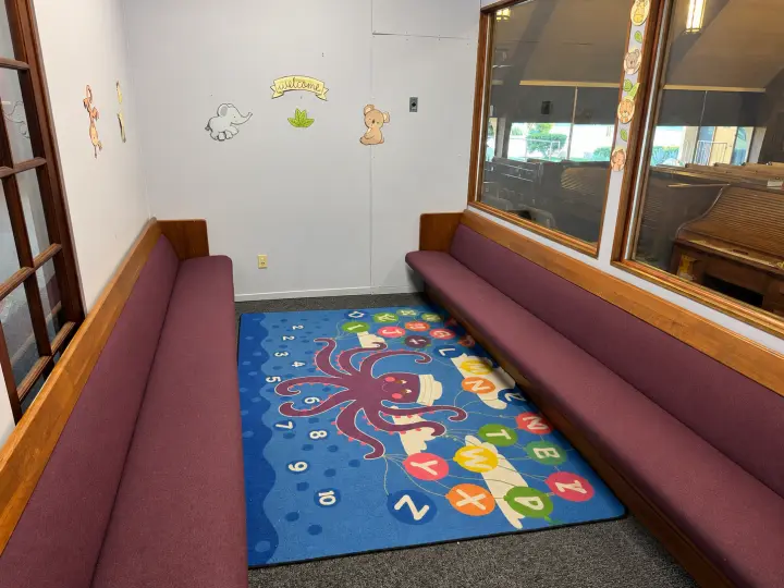 Children's waiting area with built-in benches and a colorful octopus alphabet rug